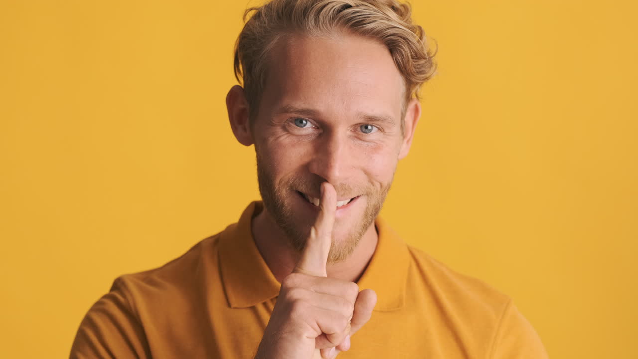 젊은 수염이 있는 남자가 비밀을 지키라고 부탁하면서 머리를 흔들고