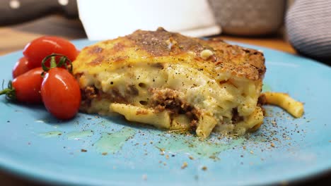 Griechisches-Essen-Pastitsio-Blauer-Teller,-Der-Nach-Links-Schwenkt