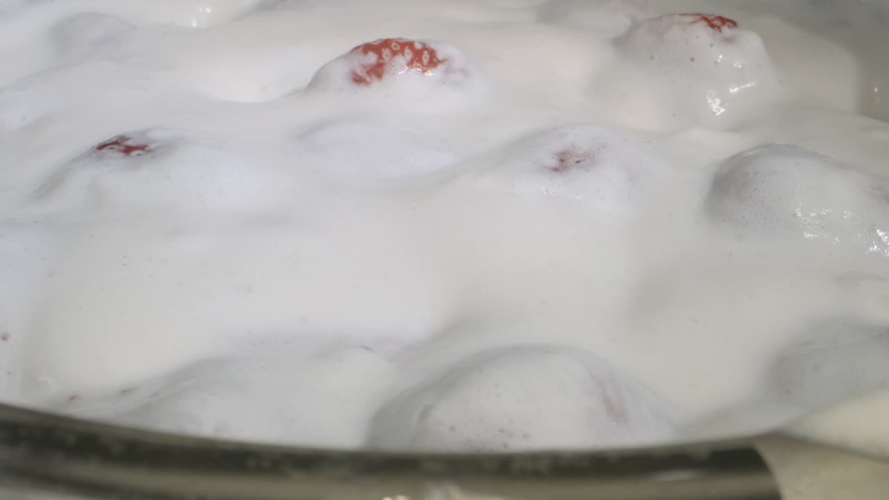 girar fresas maduras cubiertas con una capa gruesa de crema en vidrio sobre fondo negro. rotación de la cámara 360 grados, primer plano.