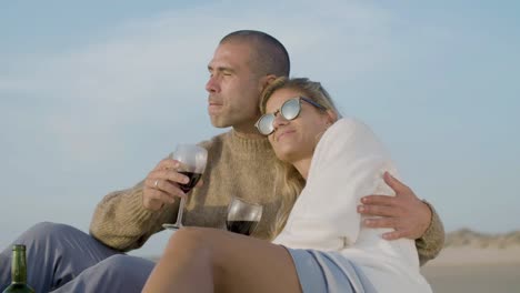 una feliz pareja caucásica bebiendo vino en la playa.
