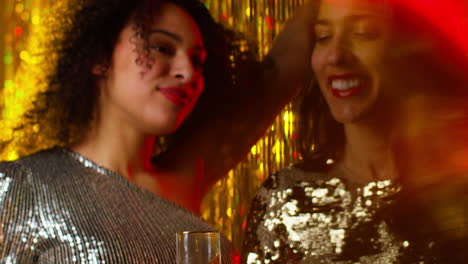 close up of two women dancing in nightclub bar or disco drinking alcohol with sparkling lights 7