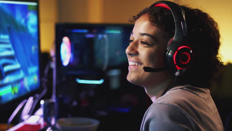 una adolescente con auriculares jugando en casa usando dos pantallas de computadora