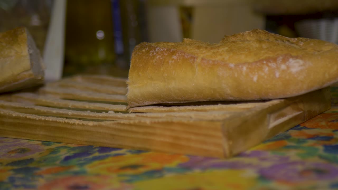 Uomo che taglia una pagnotta di pane con un coltello da pane su un tagliere di legno