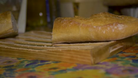 Man-cutting-loaf-of-bread-using-bread-knife-on-wooden-cutting-board