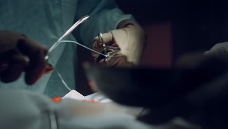 las manos del médico realizando una operación de cerca. herramientas médicas en una sala de cirugía oscura.