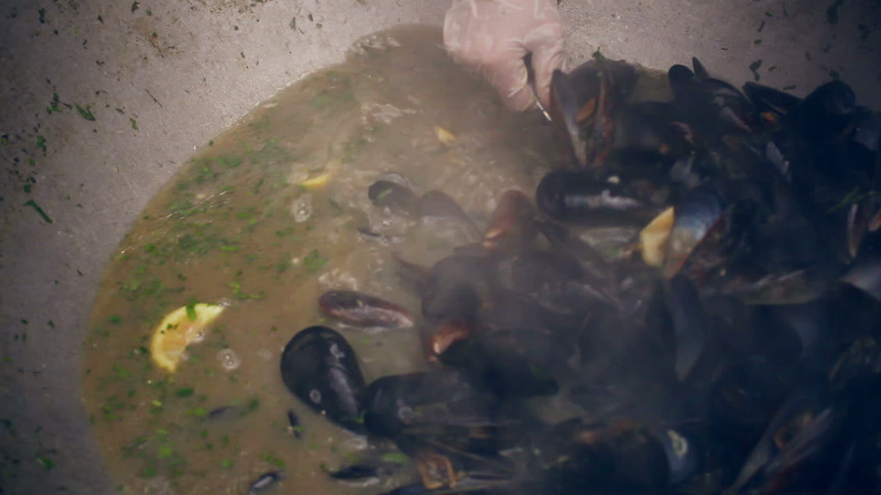 Mussels in pan. Chef takes mussel shells from pan. Delicious seafood dish