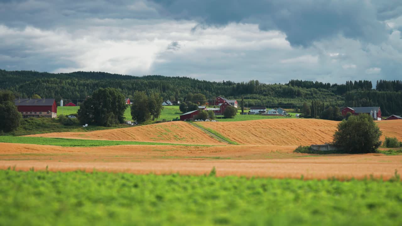A patchwork of farm fields in rural Norway Stormy clouds whirl above