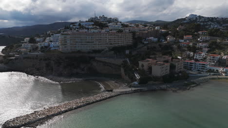 wide establishing of playa sur shoreline and cityscape under cloudy skies in peniscola, spain