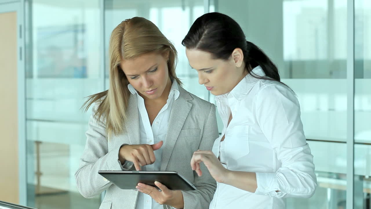 Two Attractive Women Looking At The Screen Of A Tablet