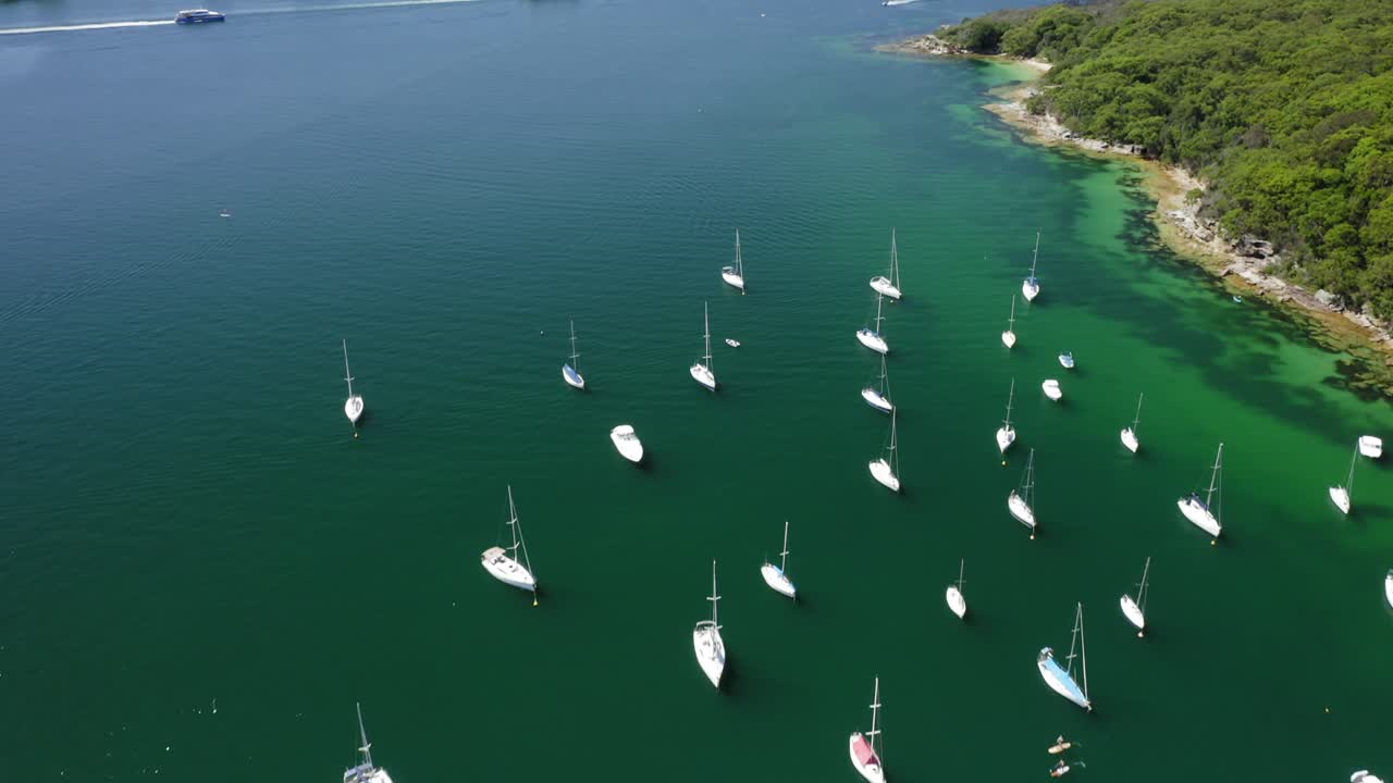 Rising aerial view of the Davis Marina revealing Sydney Harbour entrance and the Manly Ferries on clear blue day.