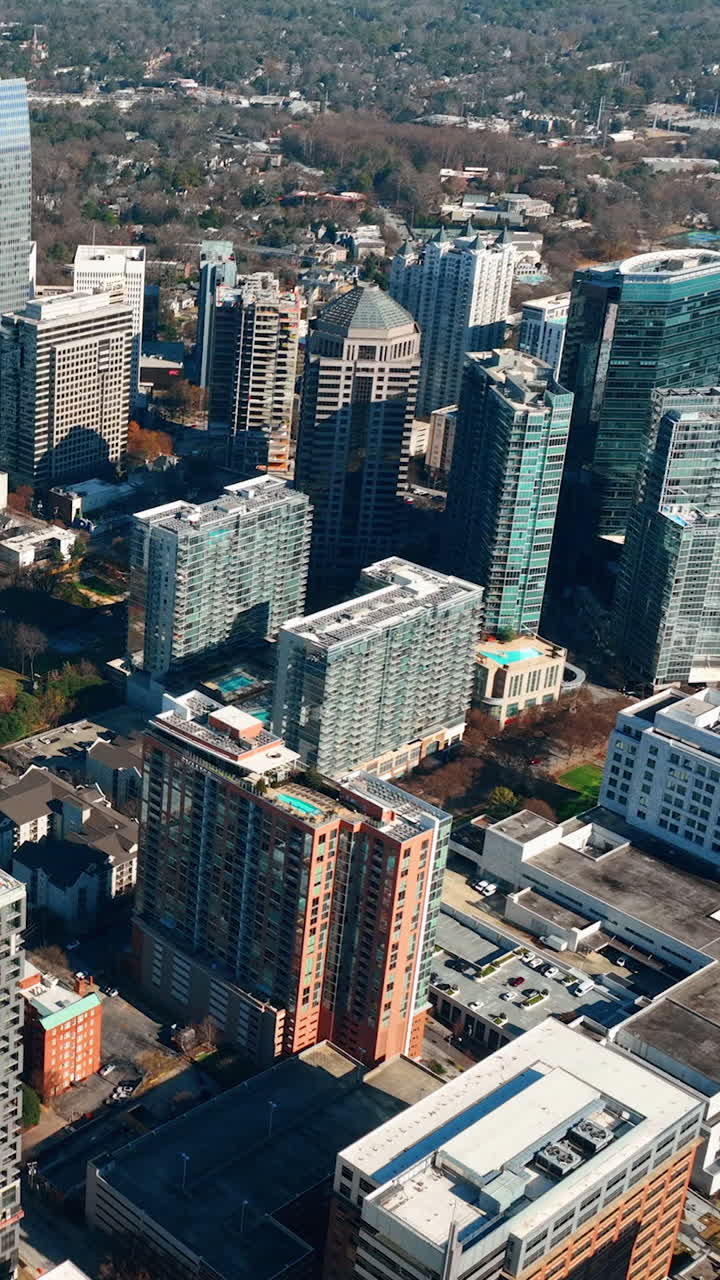 Vista aérea do centro de Atlanta, Geórgia. Arranha-céus altos, construção com guindastes, parque de outono. Dia ensolarado. Vista aérea de Atlanta Buckhead. Vídeo vertical