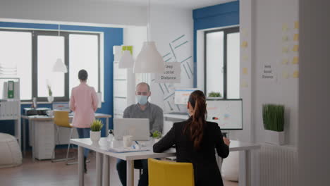 collegues with face masks greeting each other with elbow