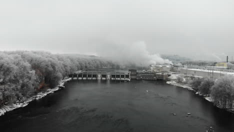 river dam in the winter surrounded with frost covered trees