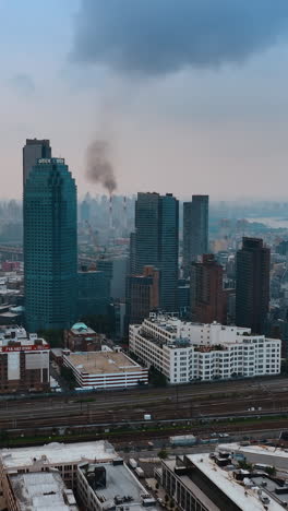flight above new york on a grey dull day. overcast sky over metropolis, some smoke rising up from the building at backdrop. vertical video