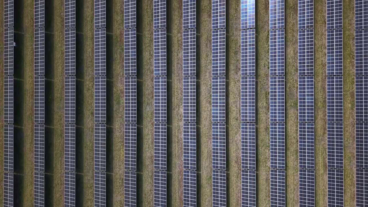Una vista aerea di file di pannelli solari fotovoltaici disposti in un grande campo, che rappresentano l'energia verde moderna e la sostenibilità.