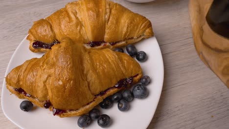 croissants con mermelada y arándanos frescos en un plato blanco. vista de arriba.