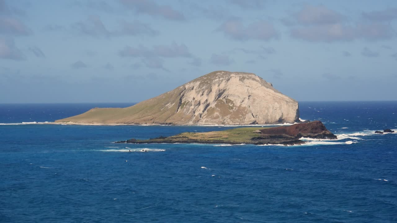 태평양을 배경으로 하고 일부 초목이 보이는 동해안의 오아후 해안에 있는 작은 섬