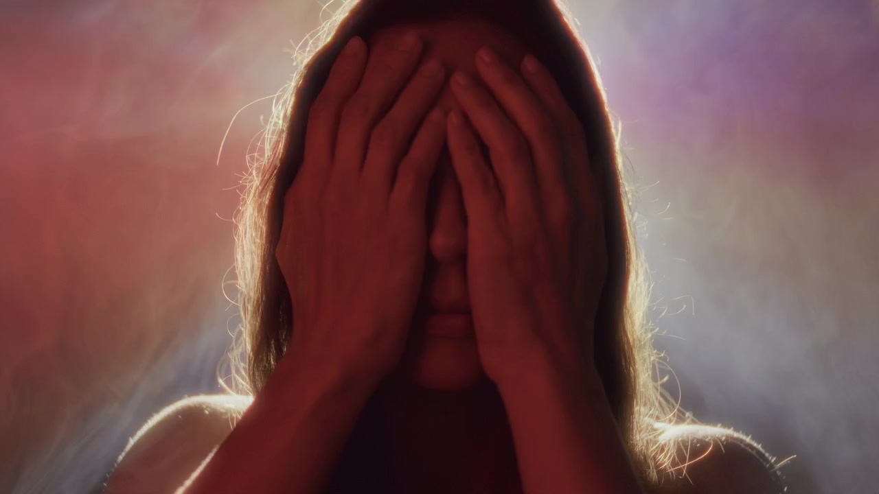 Mulher Cobrindo os Olhos com as Mãos em Luzes Neon e Fumaça