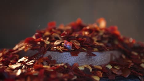 flakes of red hot chili pepper in wooden spoon closeup on a kitchen table.