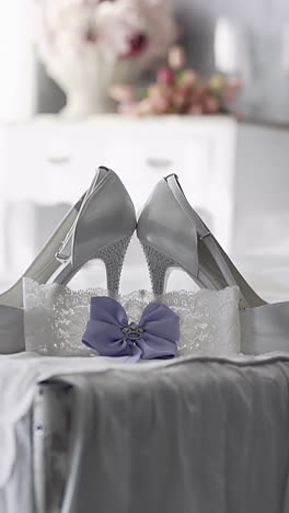 slow motion lacy garter with pink bow put near white high heeled shoes against wedding dress on bed