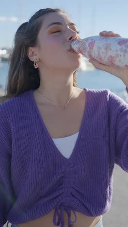 woman drinking water from a floral bottle outdoors