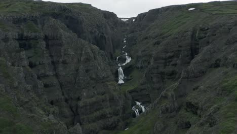 dramatic landscape with large canyon and waterfall passing through in iceland