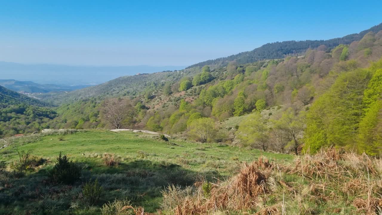 Panoramic view of Northern Greece’s mountainous landscape, stretching to the horizon under a deep blue sky, showcasing rugged peaks, valleys, and scenic natural beauty