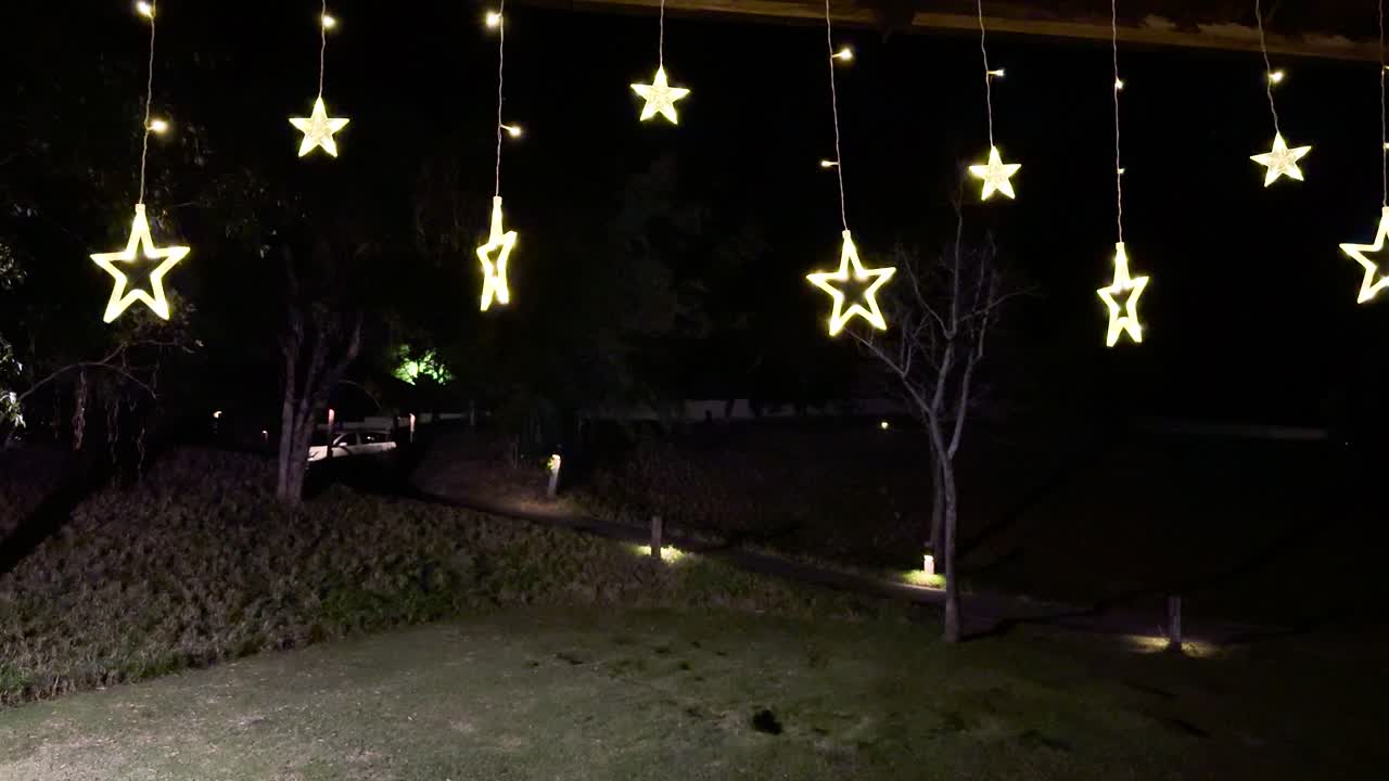 las luces de las estrellas colgantes iluminan un jardín sereno