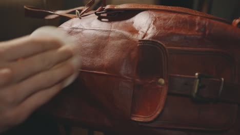 hand polishing brown leather bag with bronze latch - close up