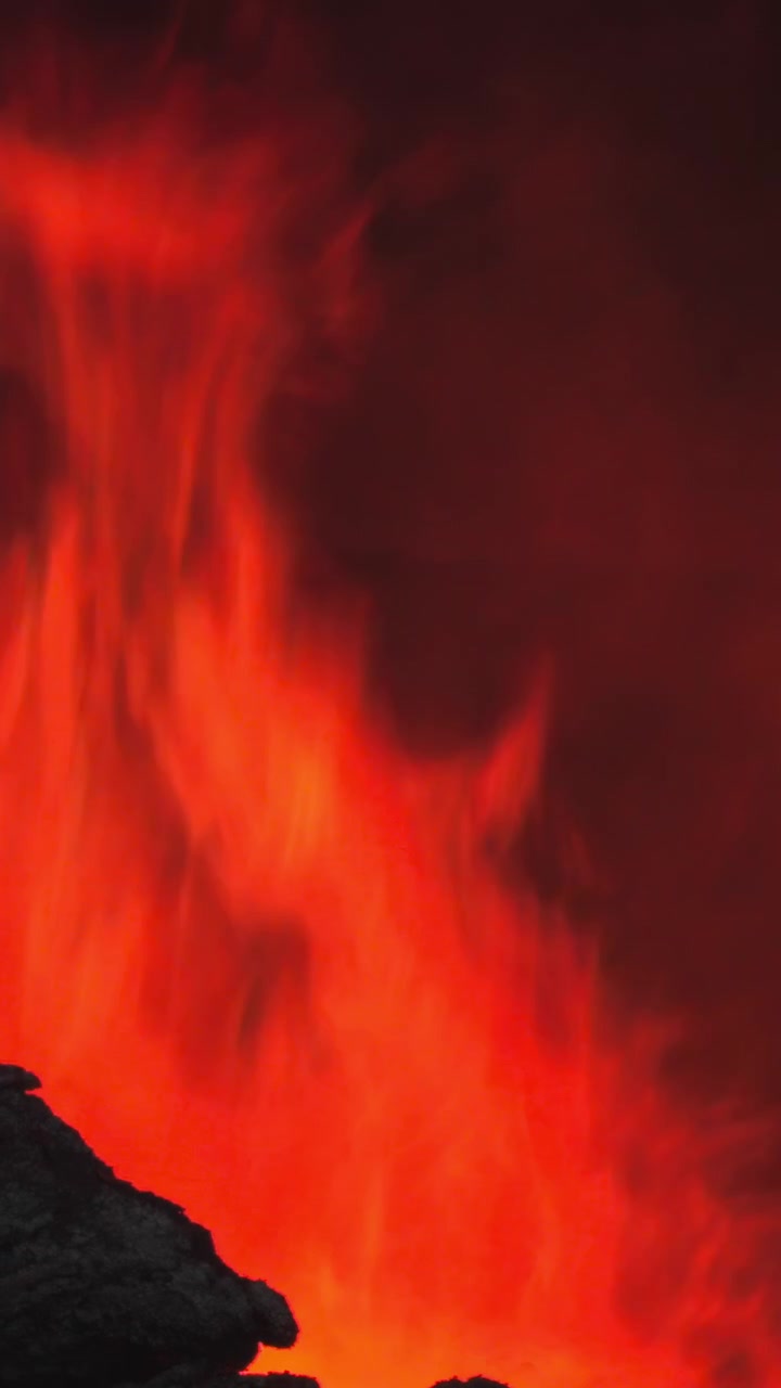 Lavaähnliche Flammenfahne steigt über felsigem Rand auf, intensives rotes Glühen und aschegefüllter Rauch, dynamische Hitzewellen