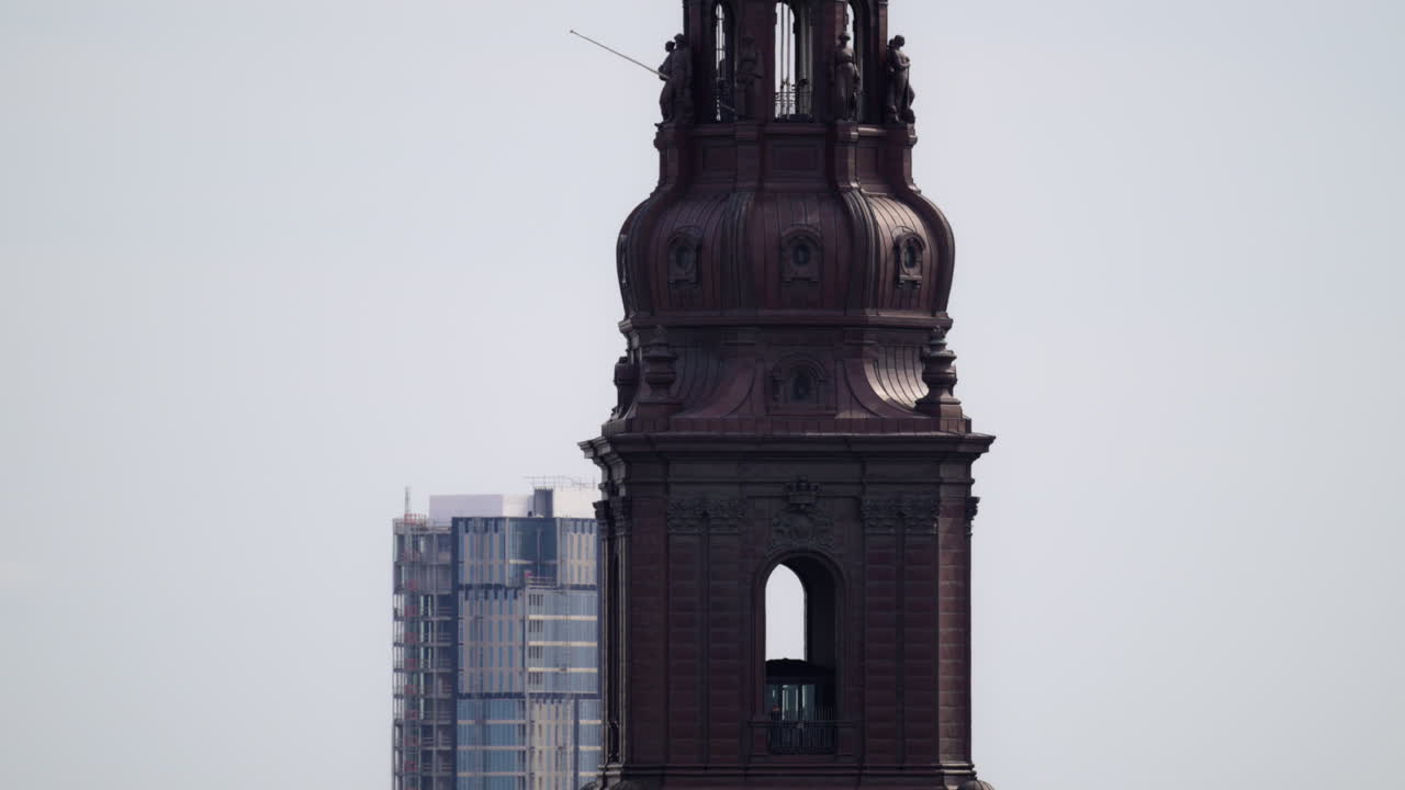 Torre del Palacio de Christiansborg con varias coronas ornamentadas bajo un cielo nublado