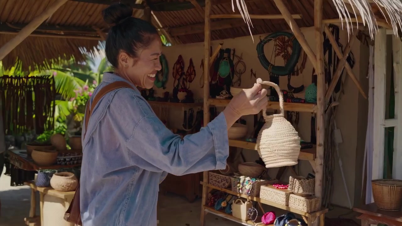 Femme heureuse faisant ses emplettes d'artisanat tissé à la main sur un marché de plage tropicale