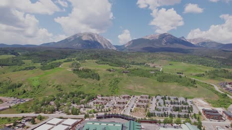 this is an aerial video of silverthorne colorado. camera pan to the right with mountains in the background and buildings in the foreground.