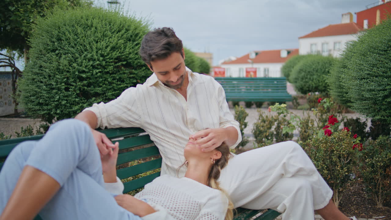 사랑에 빠진 남자가 공원 벤치에서 여자 얼굴을 만지고 있다.