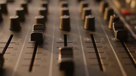 close-up of an audio mixing console faders and knobs