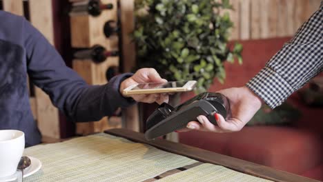 woman paying in restaurant by smart phone using nfc technology