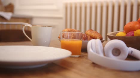 Teenager&#039;s Hand Reaching for Croissant on Breakfast Table, Slow Motion