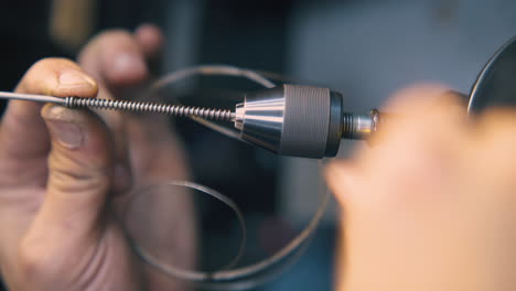 jeweler uses tool to coil gold cable in workshop closeup