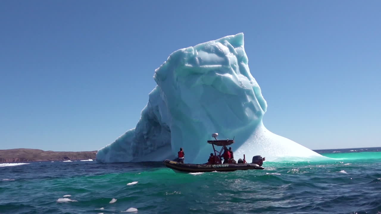 조디악 보트의 연구원이 북극 2에서 거대한 빙산을 통과합니다.