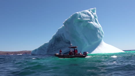 researchers in a zodiac boat pass a massive iceberg in the arctic 2