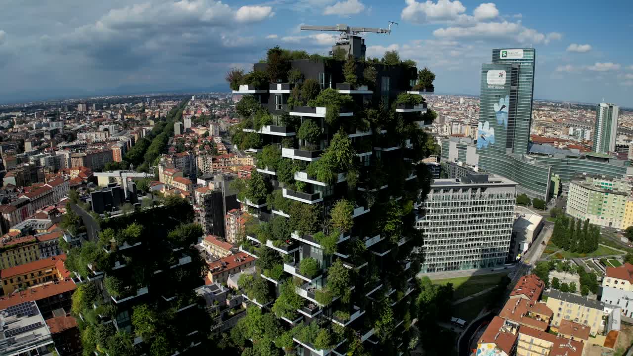 Cinematic drone footage captures a city’s core, highlighting a towering building covered in lush greenery, blending vertical forest design with the urban landscape.