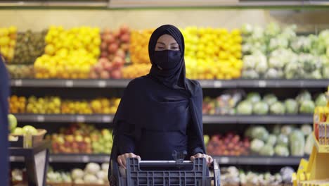 Woman-in-hijab-doing-grocery-shopping-in-supermarket,-wearing-mask