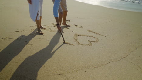 man drawing i love you on sand at seaside