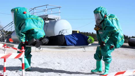 two-people-in-hazmat-suit-carrying-person-on-stretcher-to-safety