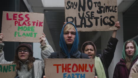 close up view of multicultural group of young activists holding cardboard placards protesting against climate change looking at camera