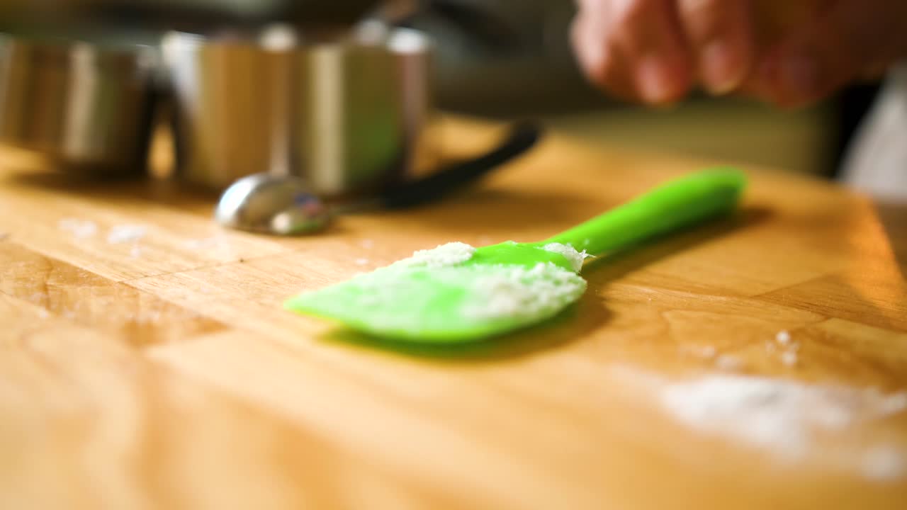 close up person picking up and putting down bright green spatula for baking