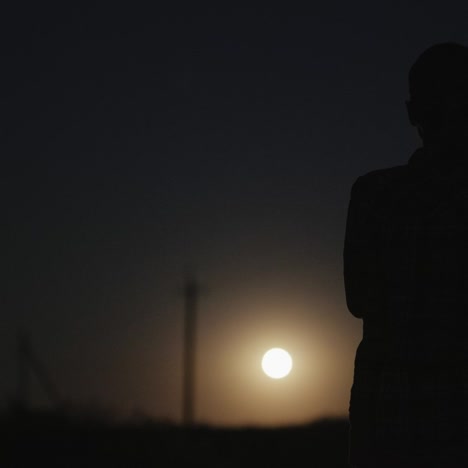 a woman looks at the moon in the dark