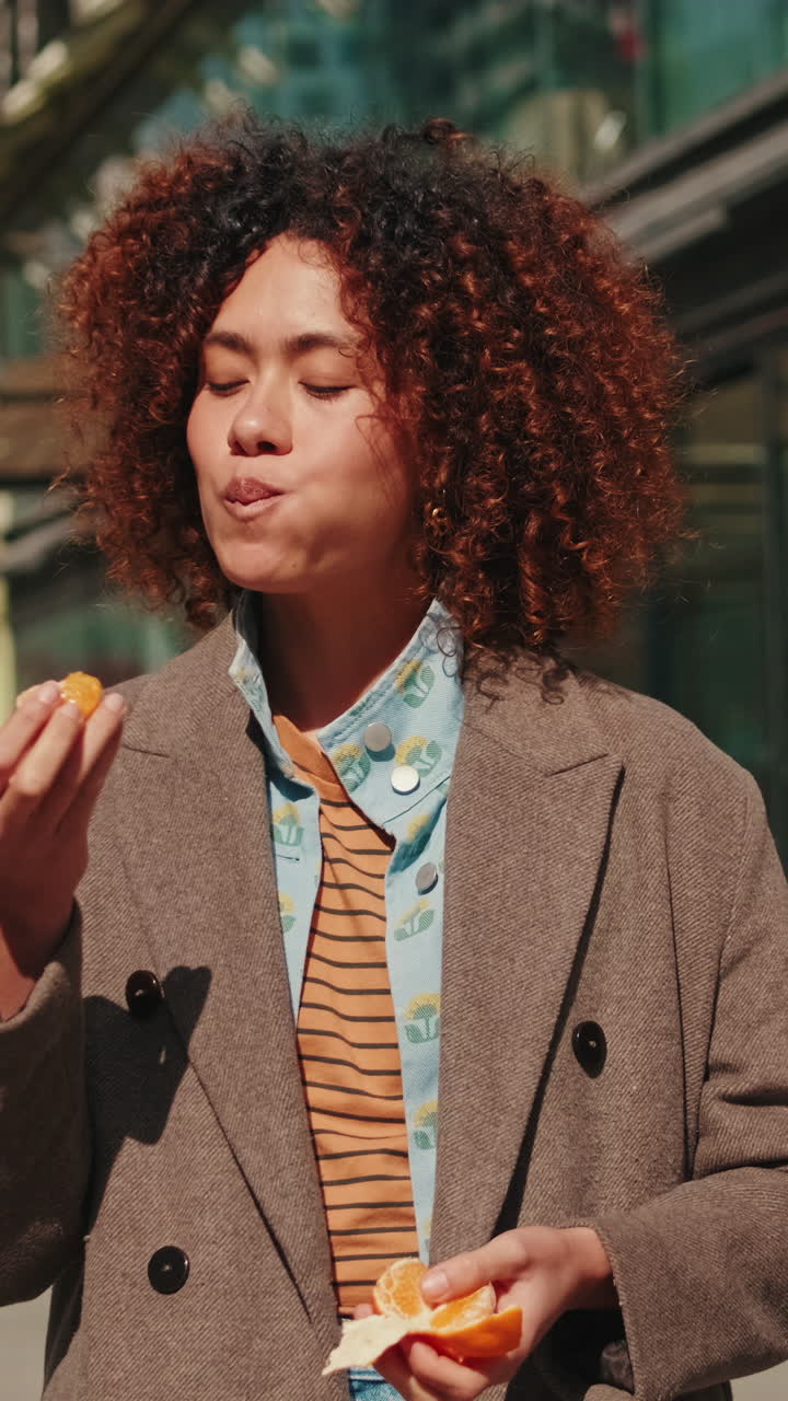 Young Woman Eats Orange in the City