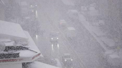 heavy snowfall on an urban street with cars