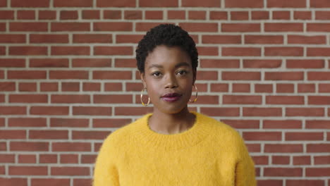 Retrato-De-Una-Elegante-Mujer-Afroamericana-Con-Camiseta-Amarilla-Que-Parece-Confiada-En-El-Fondo-De-La-Pared-De-Ladrillo